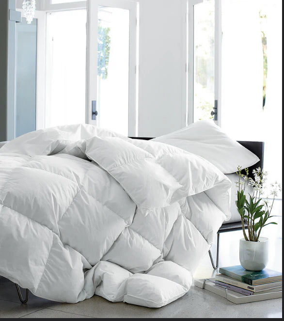 White sewn-through comforter draped over a chair in a bright bedroom
